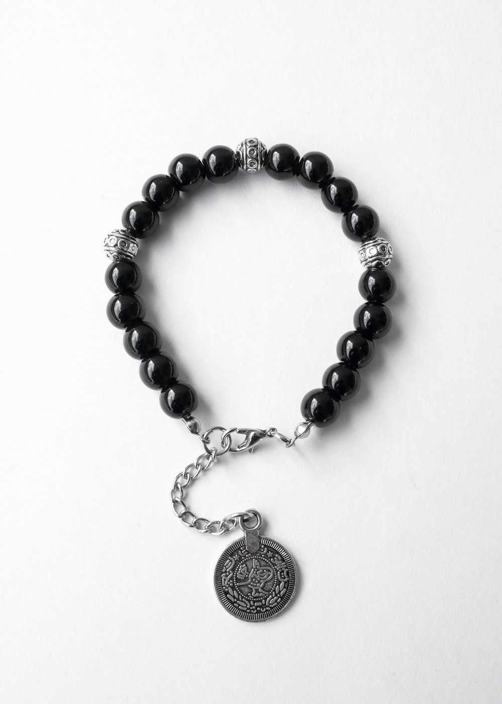 a black beaded bracelet with a silver charm