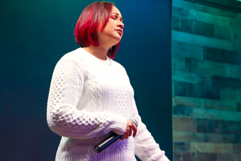 a woman with red hair standing in front of a microphone