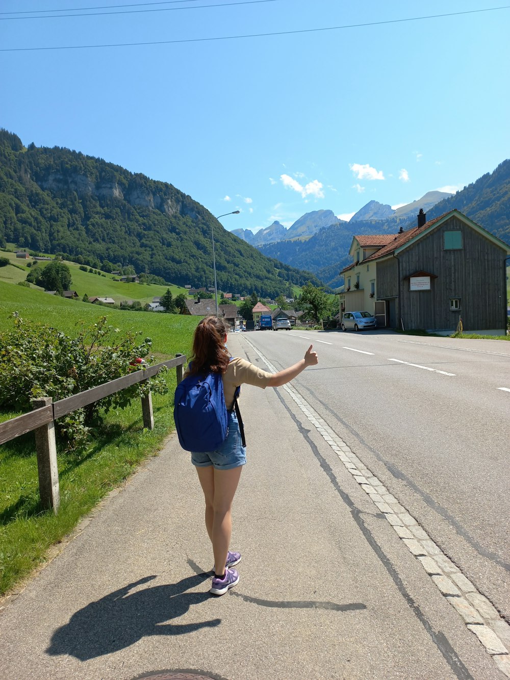 a woman walking down a road with a backpack on her back