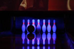 A vibrant bowling lane with colorful pins set up and glowing neon lights overhead.