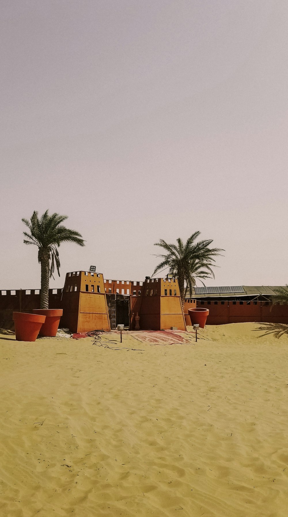 a desert scene with a building and palm trees