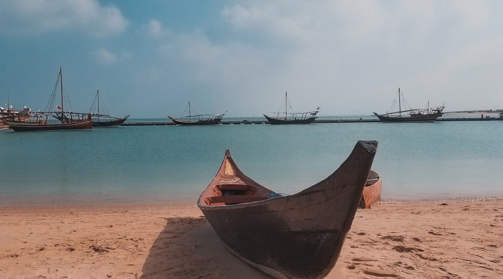 a row of boats sitting on top of a sandy beach