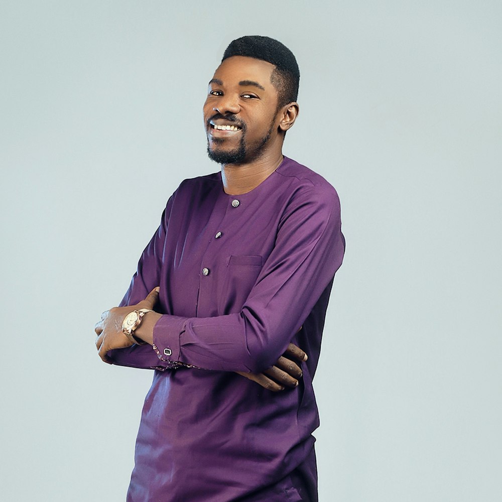 a man in a purple shirt standing with his arms crossed