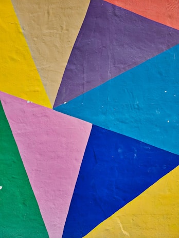 Group of students collaborating on a project, with colorful triangular patterns inspired by Rarámuri designs on the walls.