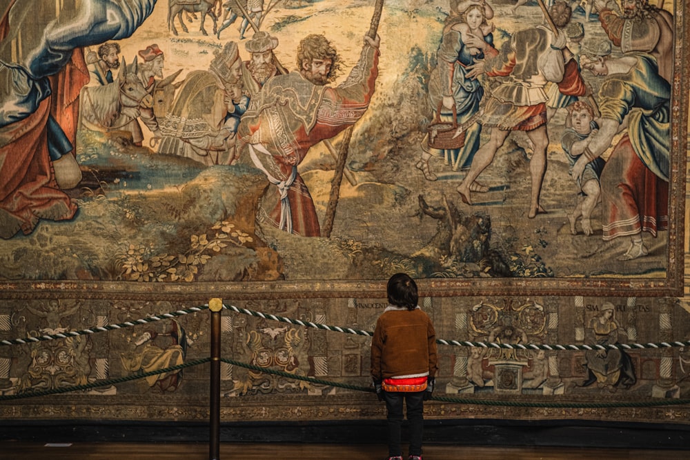 a young boy standing in front of a large painting