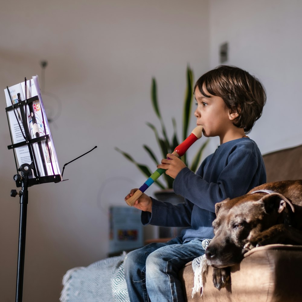 a young boy sitting on a couch with a dog