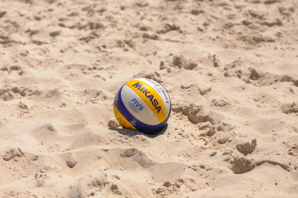 a volley ball laying in the sand on a beach