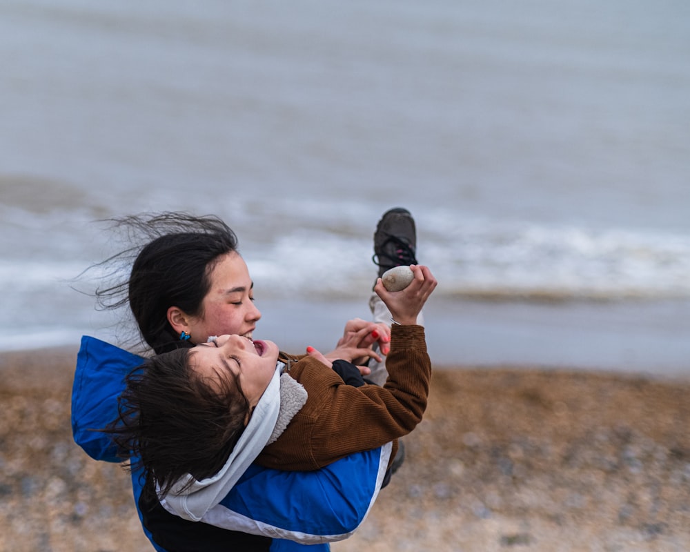 a woman holding a baby and taking a picture with a cell phone