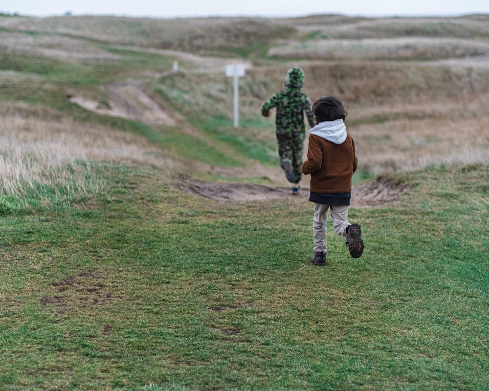a young boy running across a grass covered field