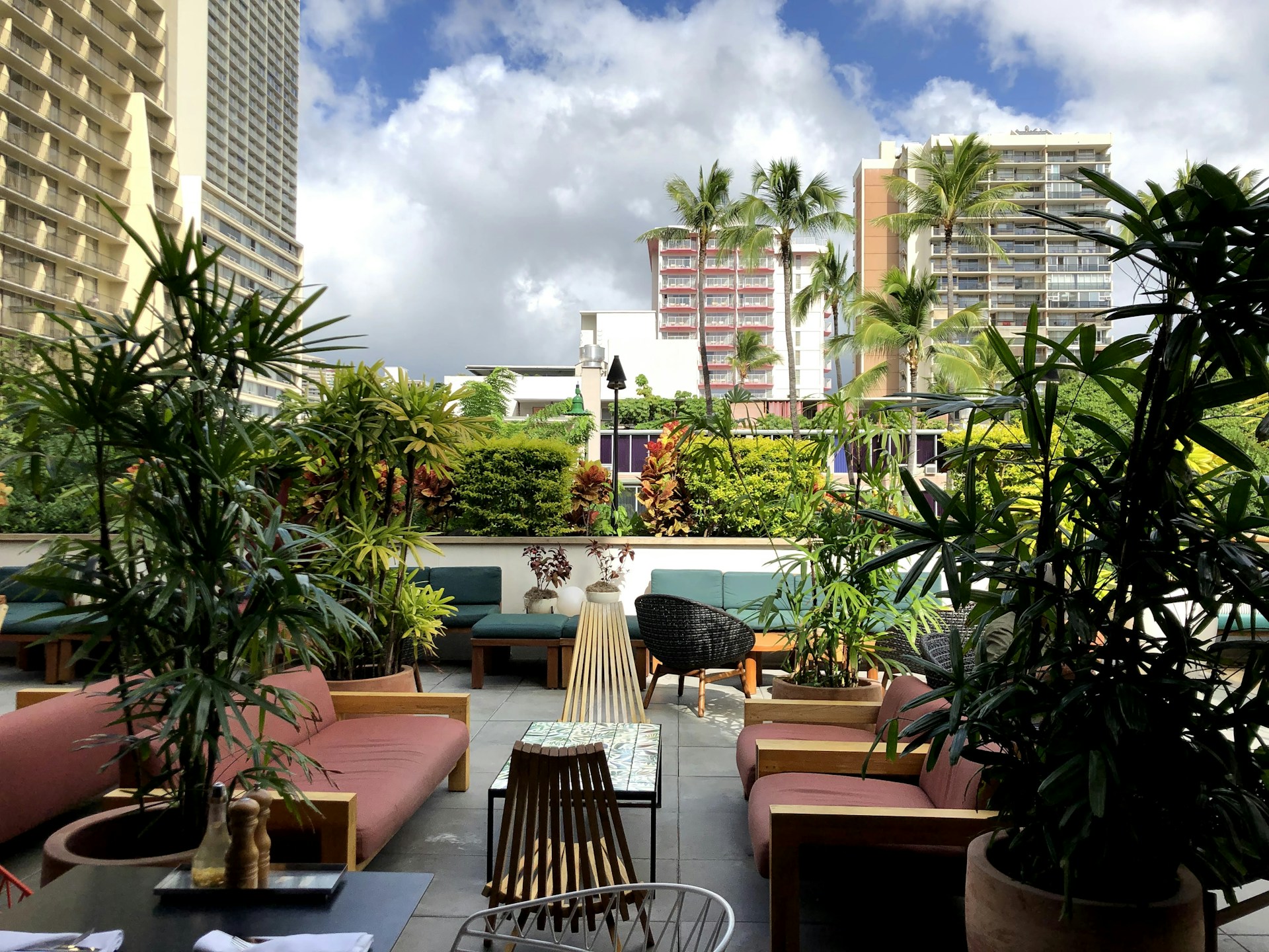 A cozy outdoor patio beautifully arranged with contemporary furniture surrounded by lush greenery.