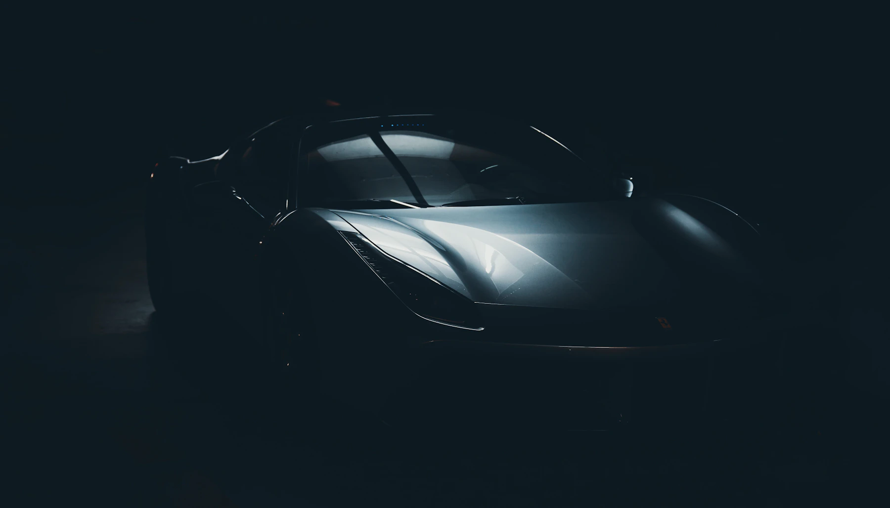 A sports car emerging from shadow in a dark studio
