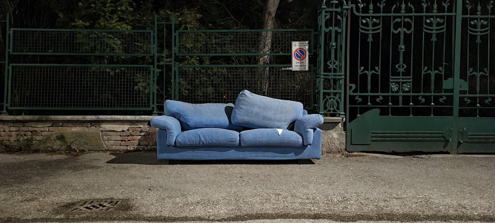 a blue couch sitting in front of a green gate