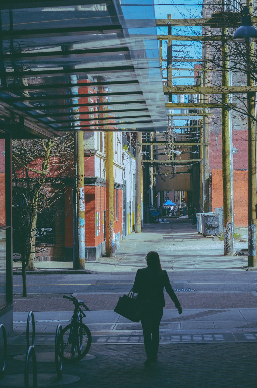 a woman walking down a street next to tall buildings