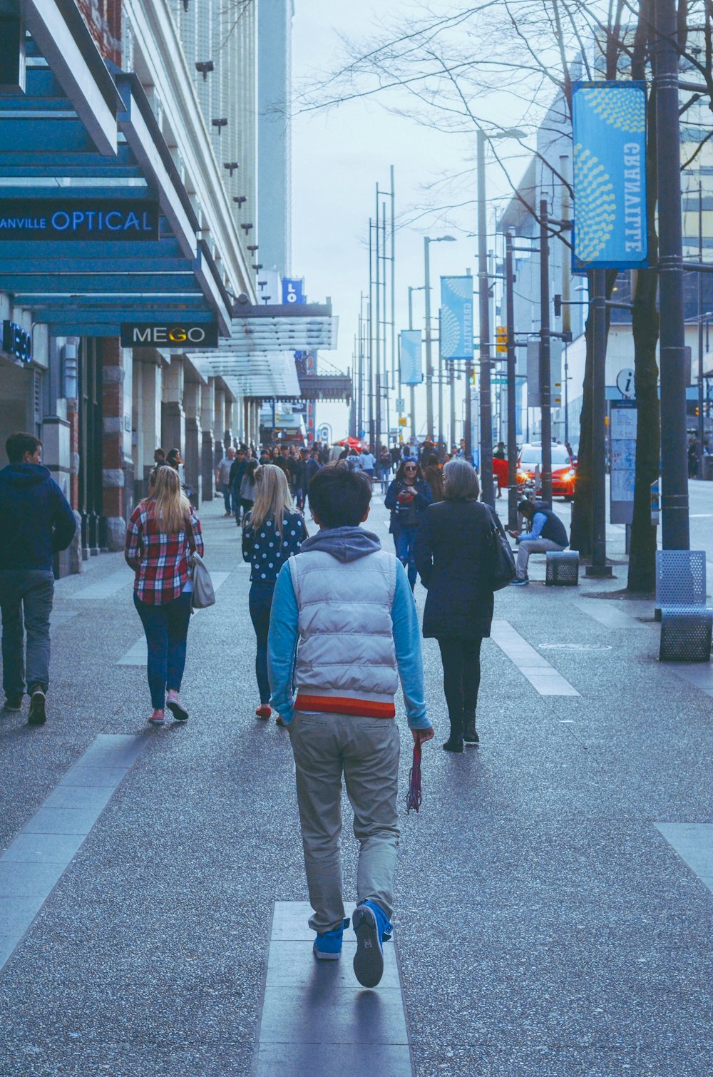 a group of people walking down a street next to tall buildings