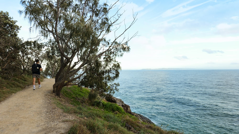 a man running down a path next to the ocean