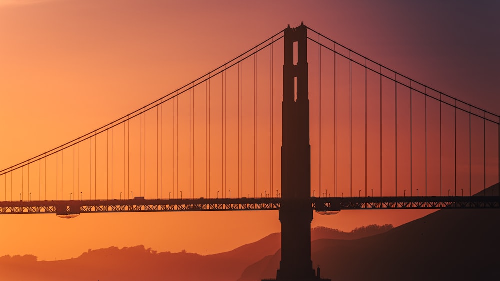the golden gate bridge is silhouetted against the sunset