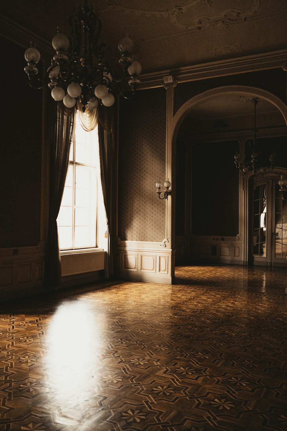 an empty room with a chandelier and a window