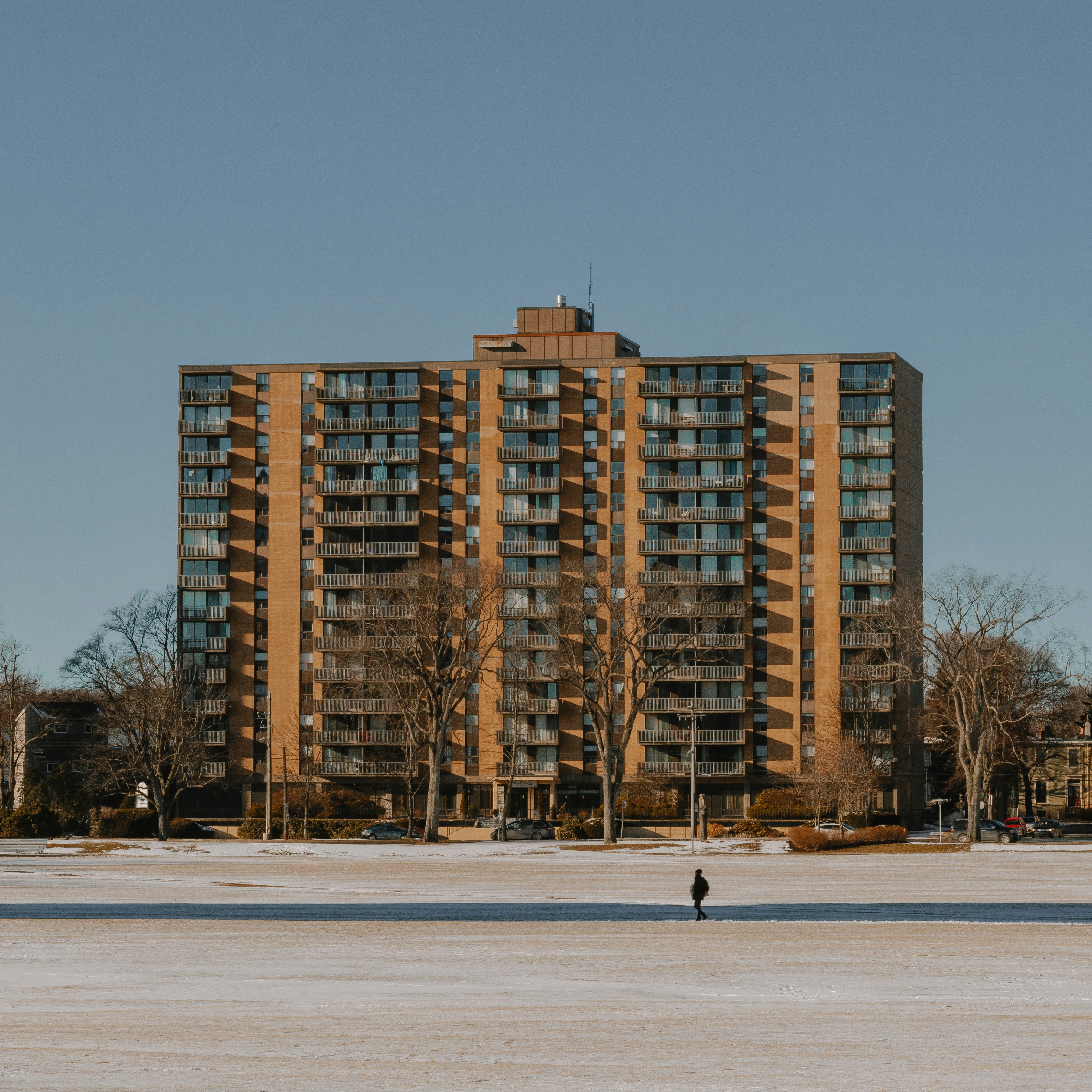 a person standing in the snow in front of a tall building