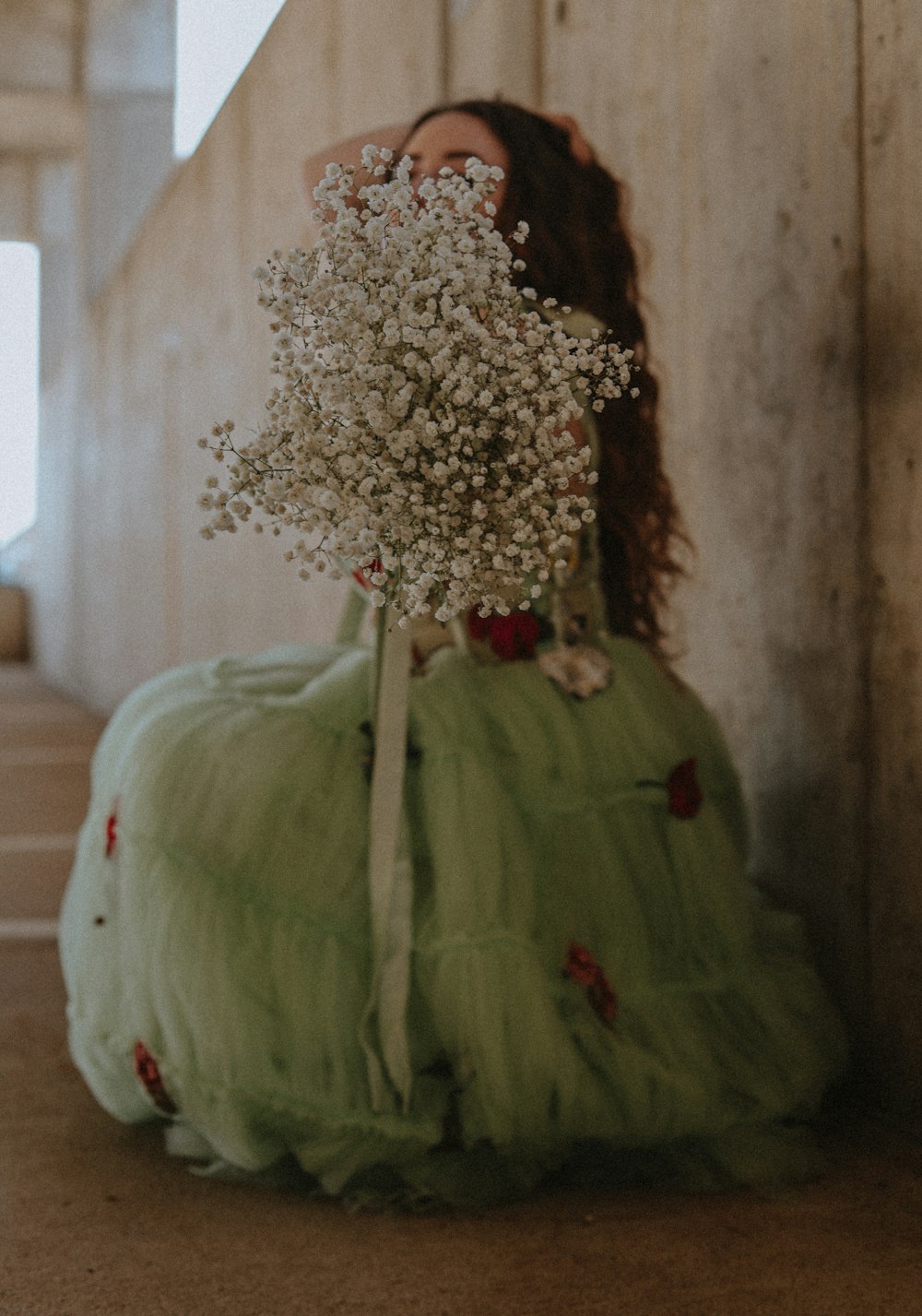 a woman in a green dress holding a bouquet of flowers