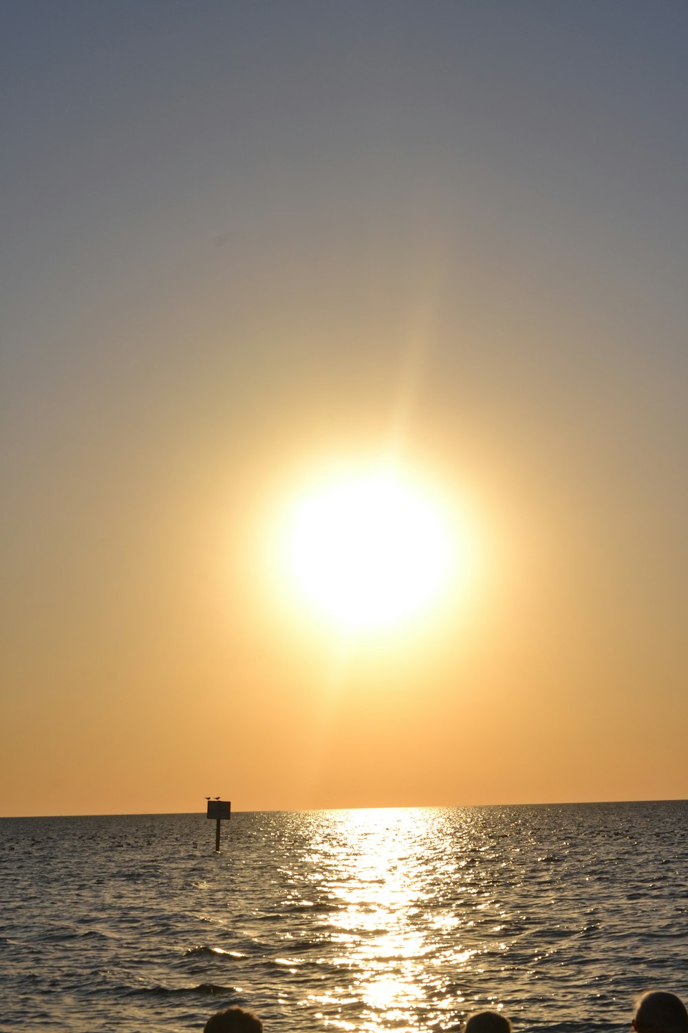 a group of people sitting on a beach watching the sun go down