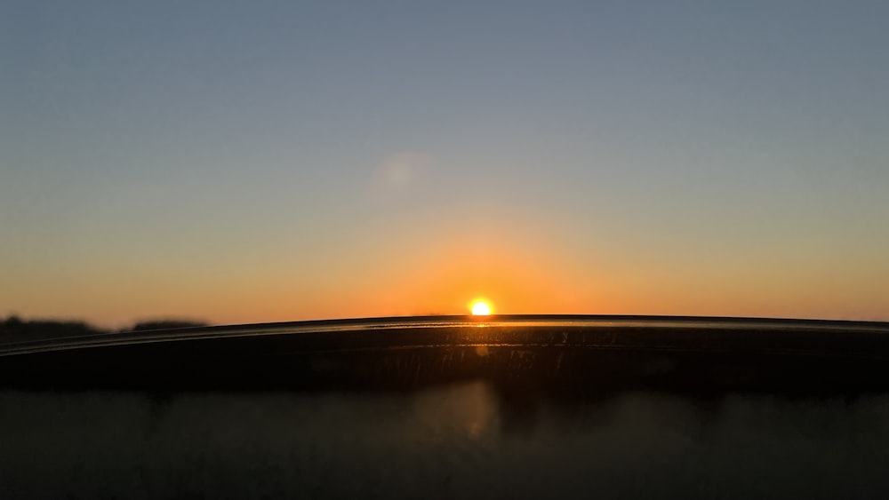 the sun is setting over the horizon of a field