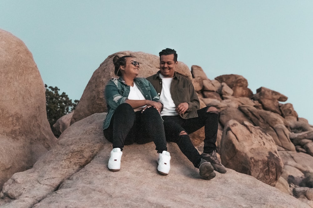 a man and a woman sitting on a rock