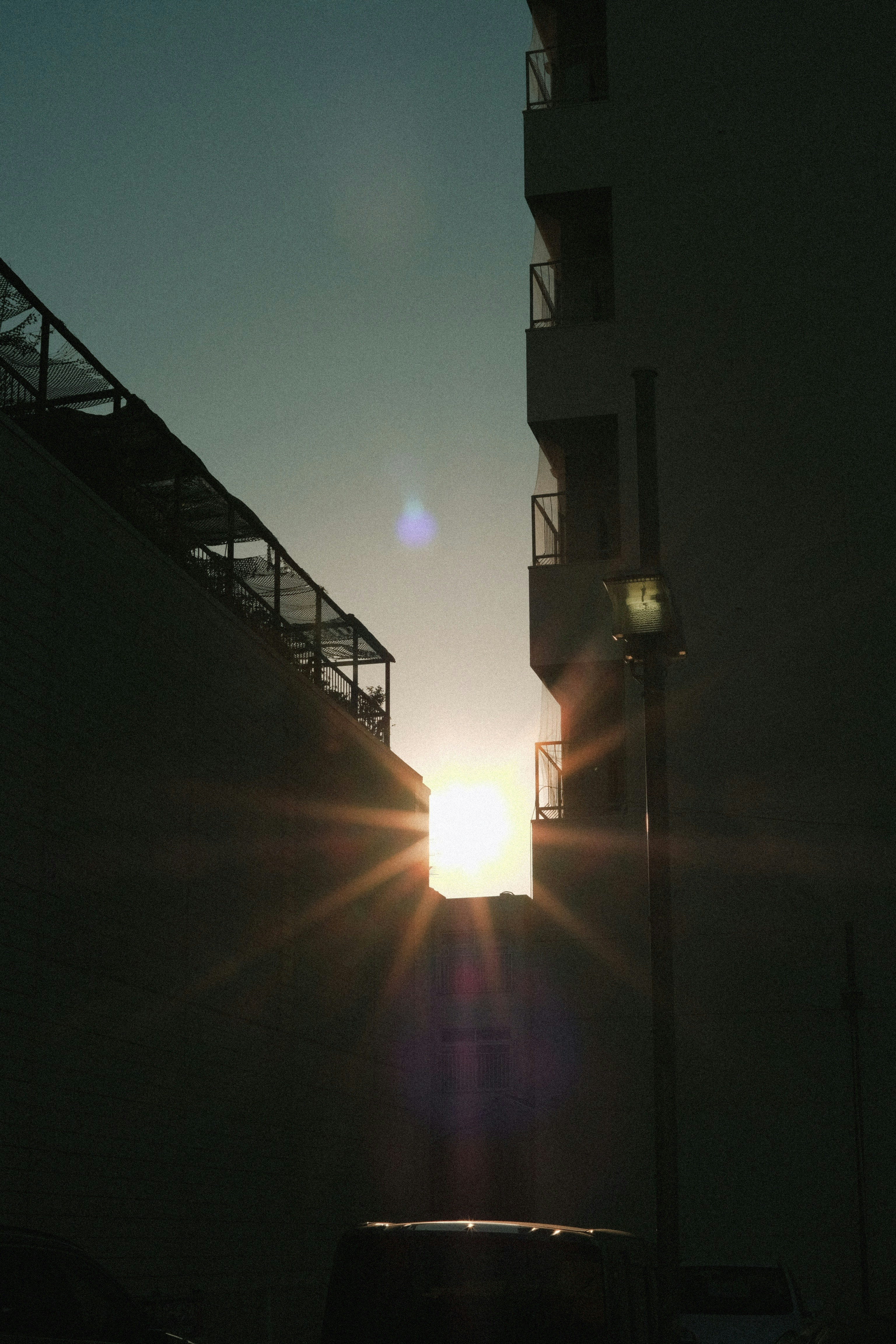 the sun is setting behind a tall building