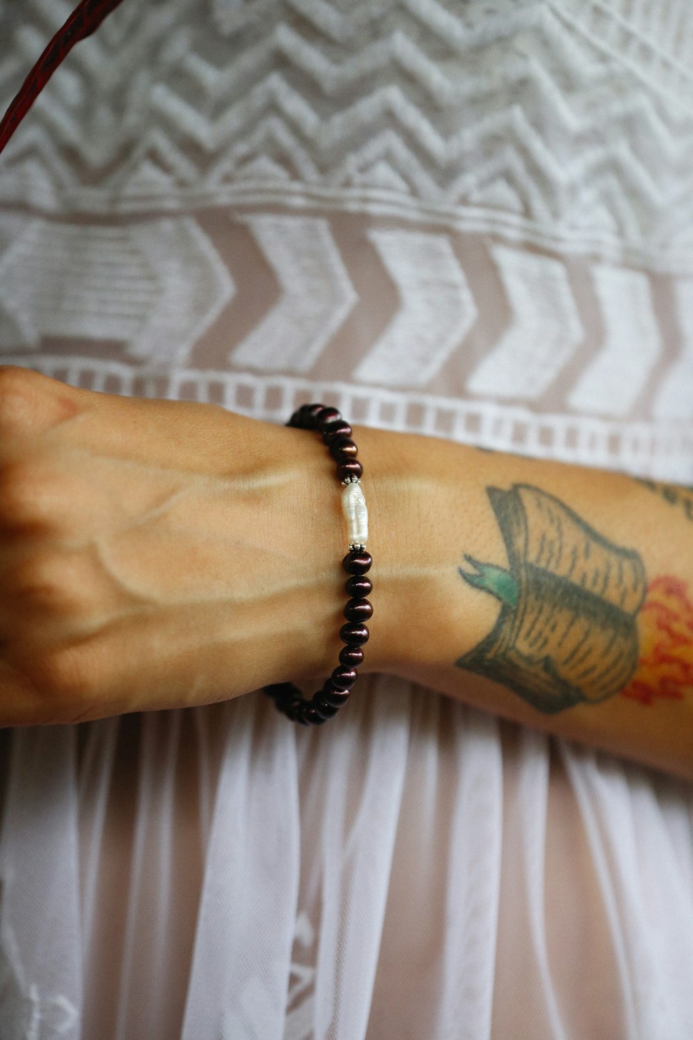 a woman with a tattoo on her arm wearing a bracelet