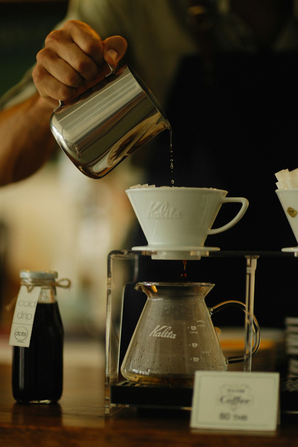 a person pours coffee into a glass pitcher