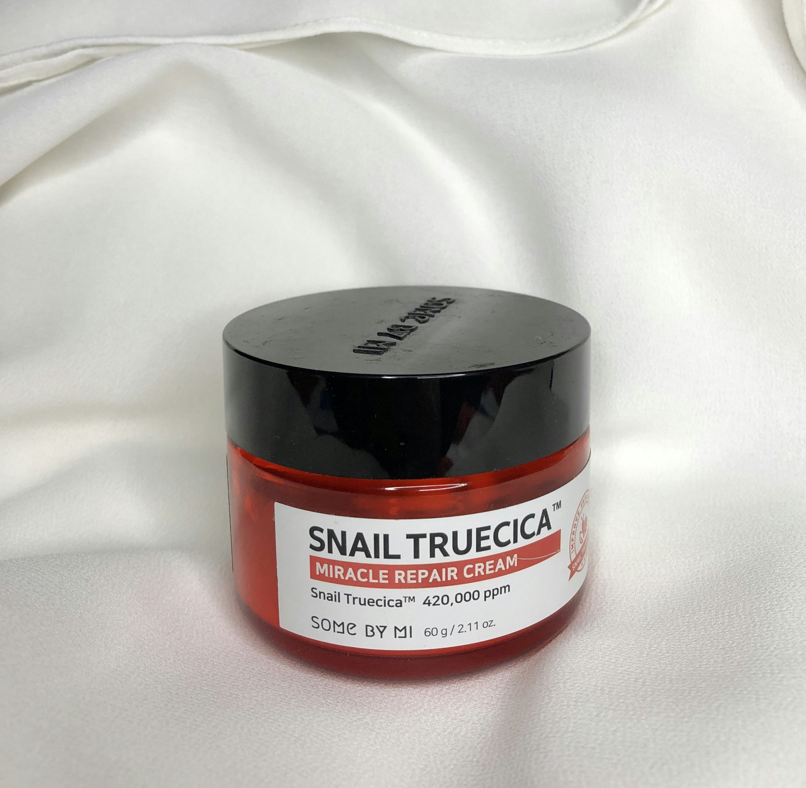 White snail mucin cream jar on cream background, Korean skincare product photography