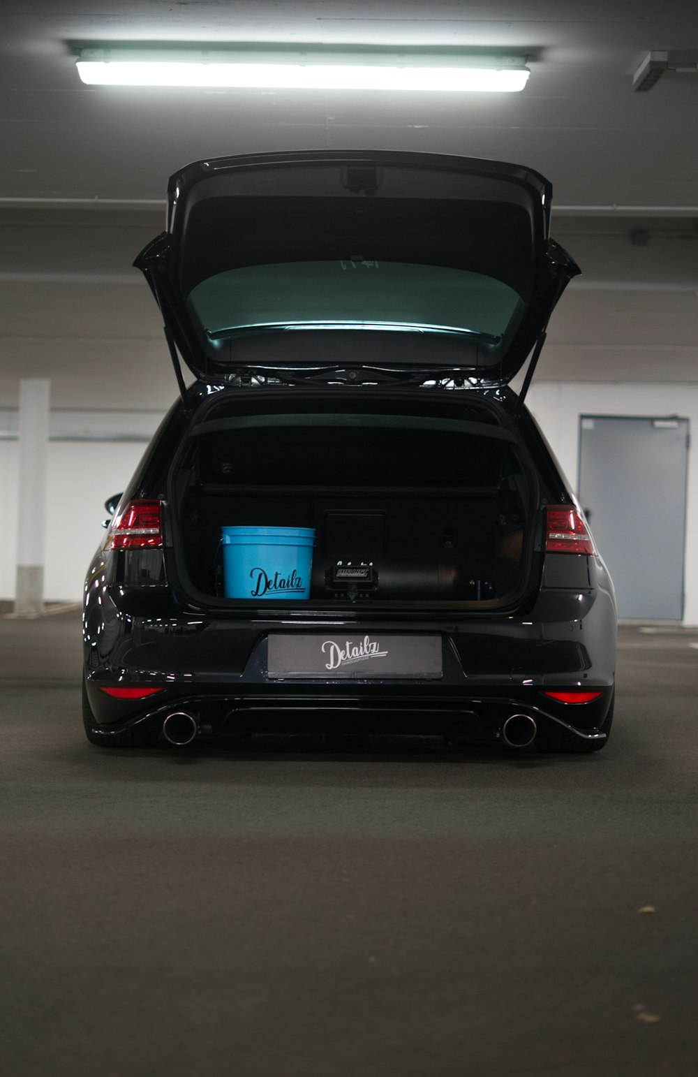 a car with its trunk open in a parking garage