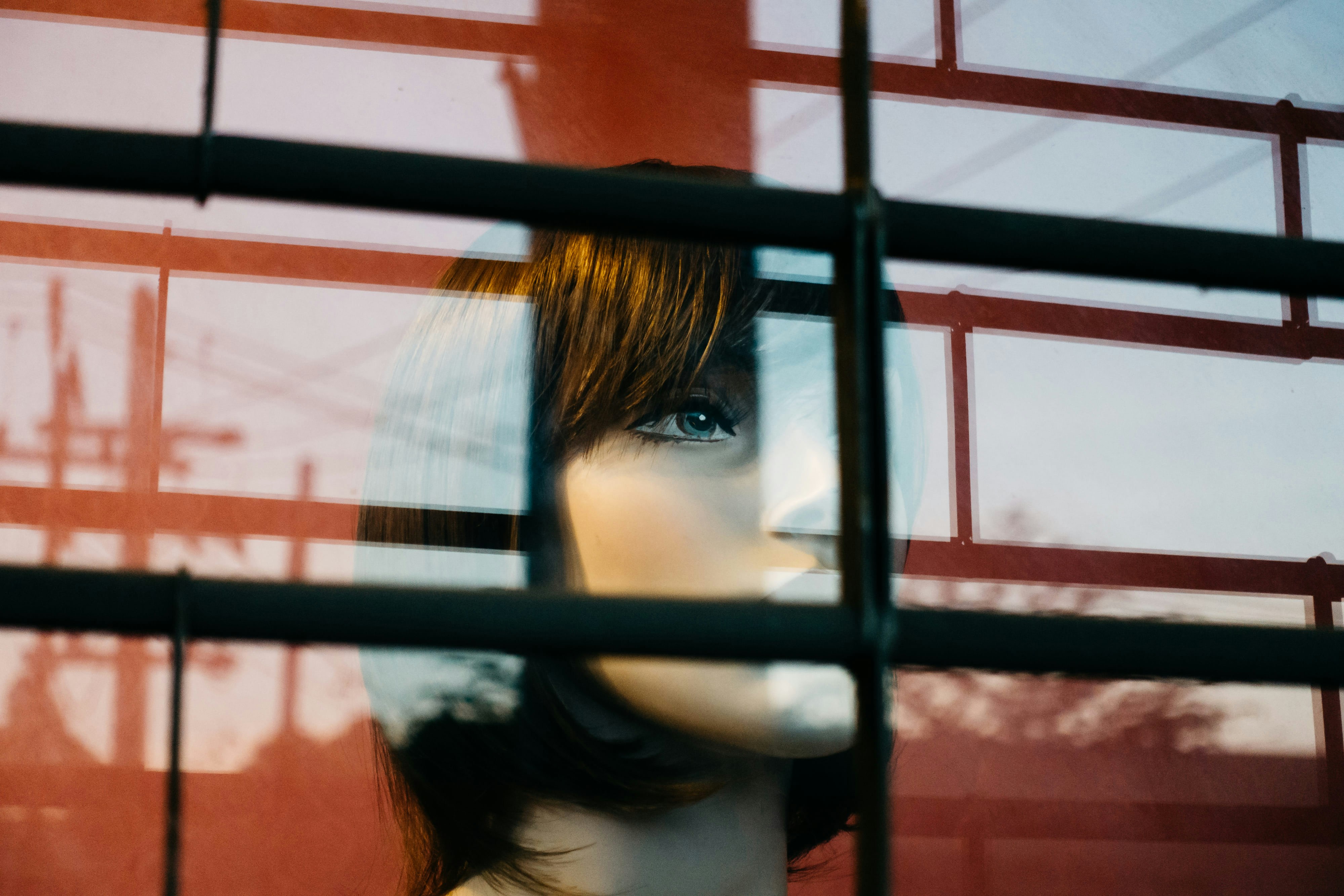 A young woman with a thoughtful expression, looking out of a window, representing silent contemplation and internal struggle.