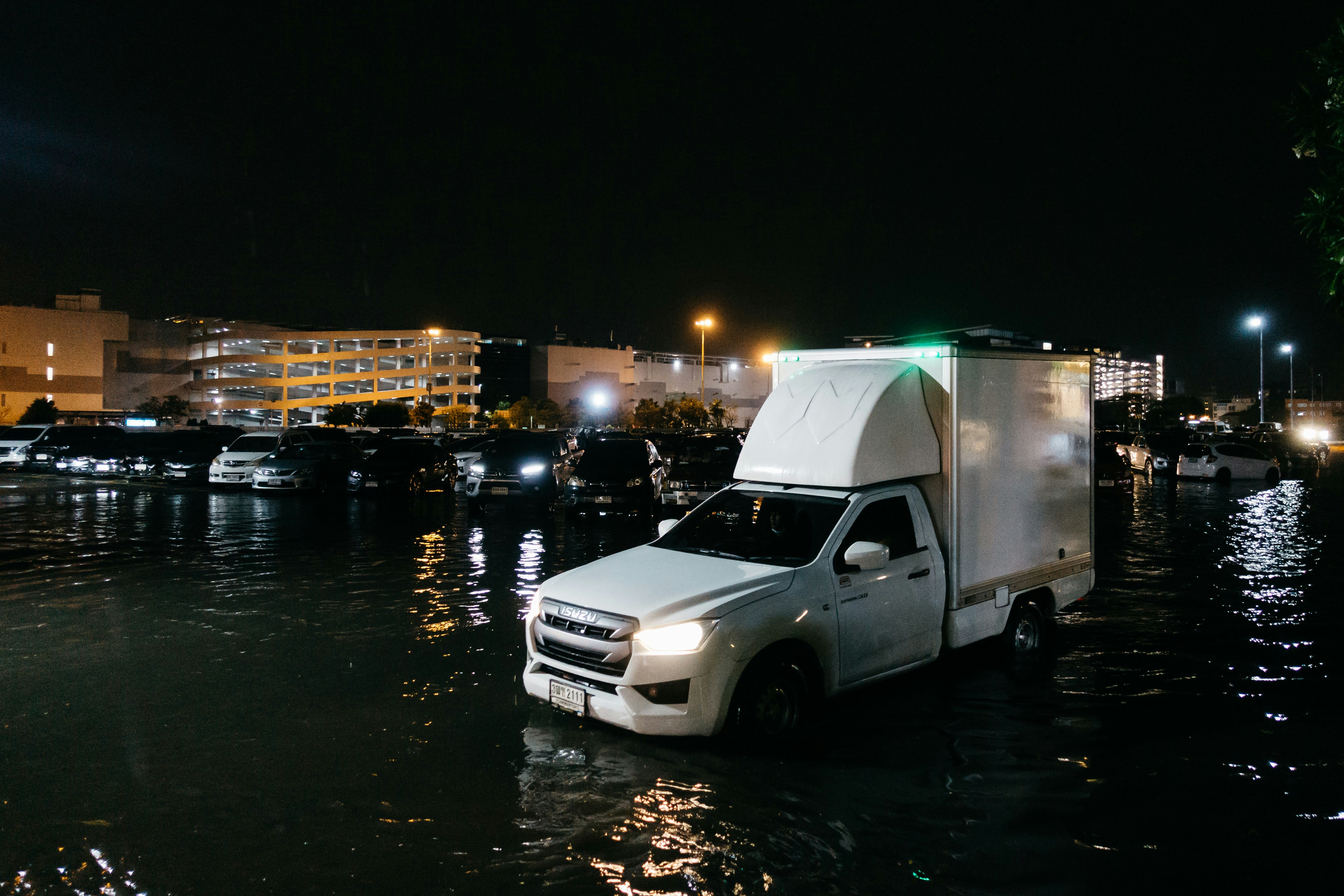 a white truck driving through a flooded street