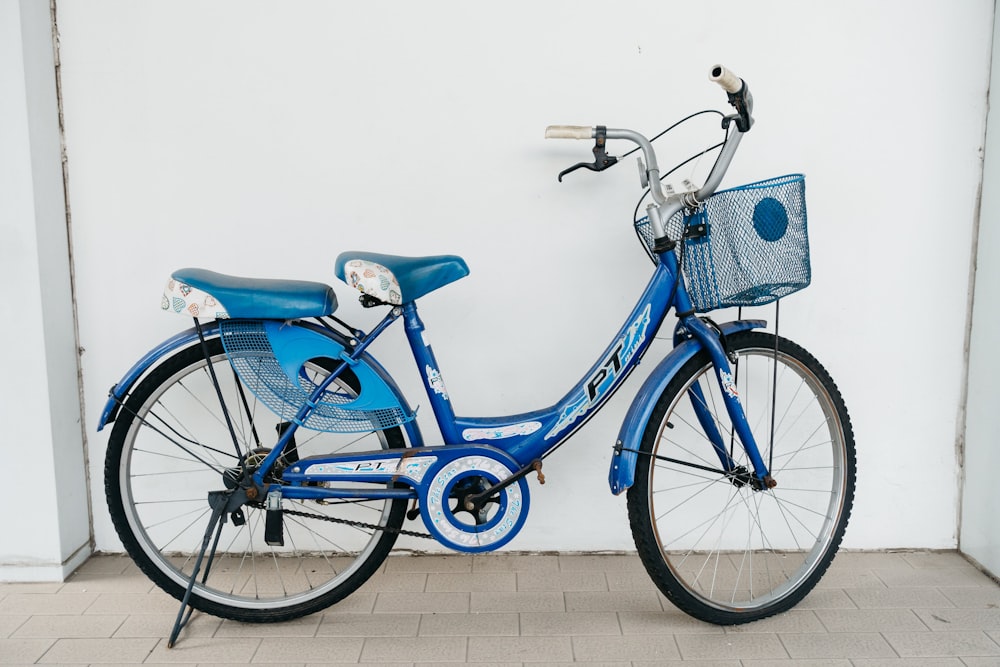 a blue bicycle parked next to a white wall