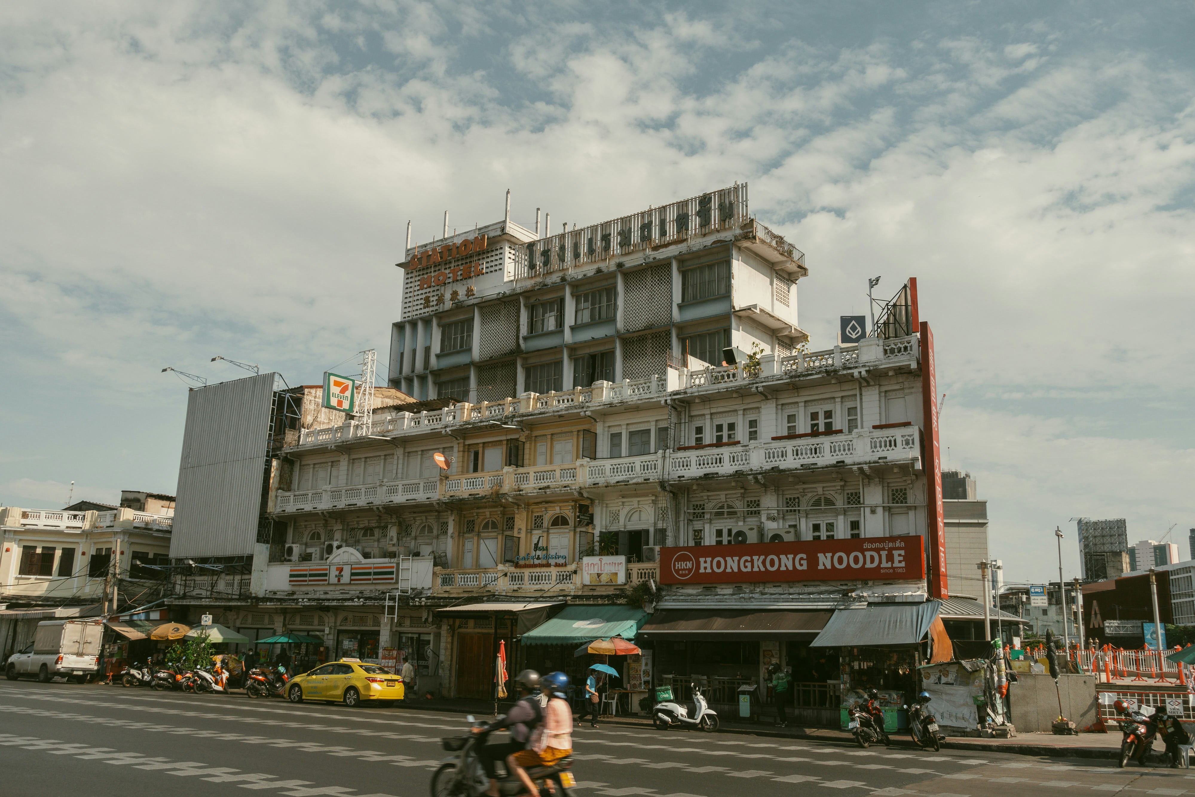 a man riding a motorcycle down a street next to a tall building