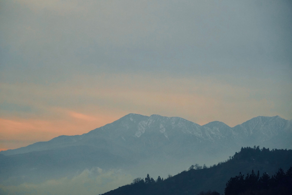 夕暮れ時に山脈の上空を飛ぶ飛行機