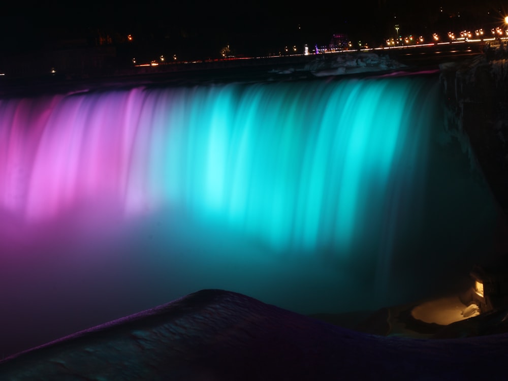 a waterfall is lit up with colorful lights