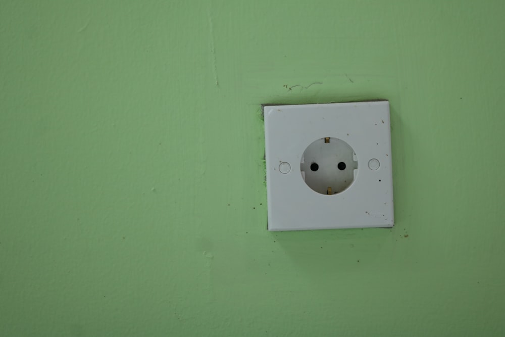a white electrical outlet on a green wall