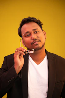 A stylish male model in an ivory shirt, holding Vesario Ignite against a black background with golden light.