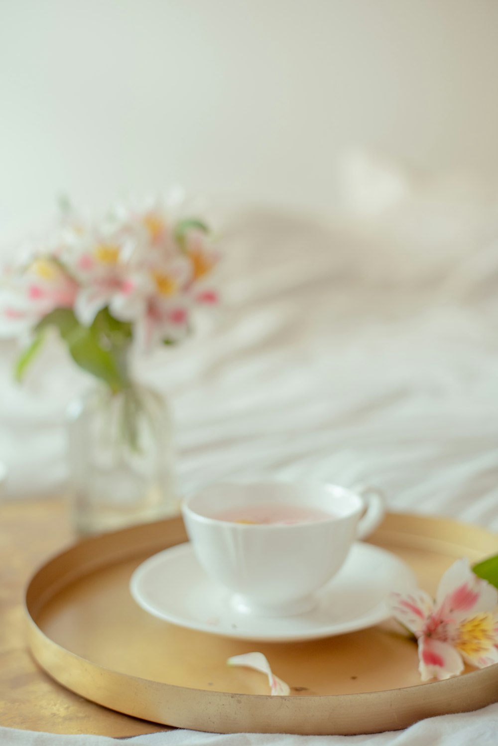 a cup and saucer on a tray on a bed