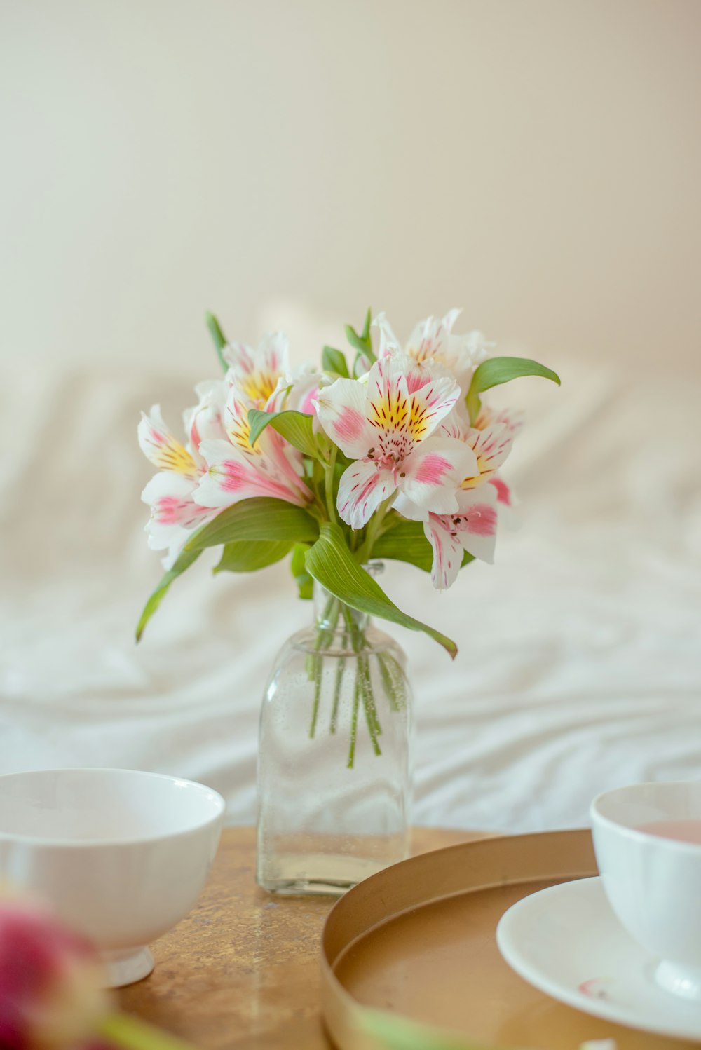 um vaso de vidro com flores rosas e brancas nele