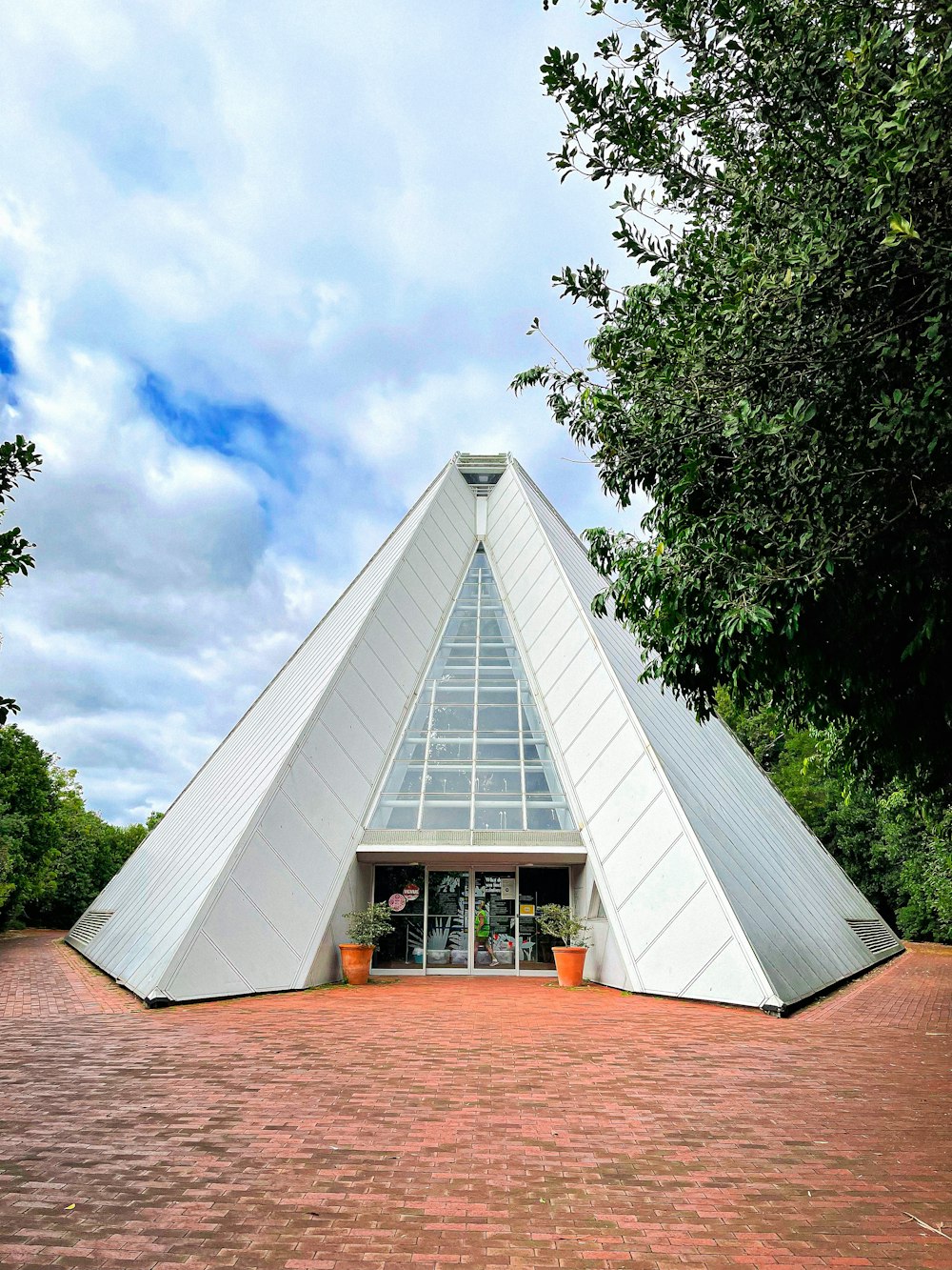 a large white triangular building sitting on top of a brick road