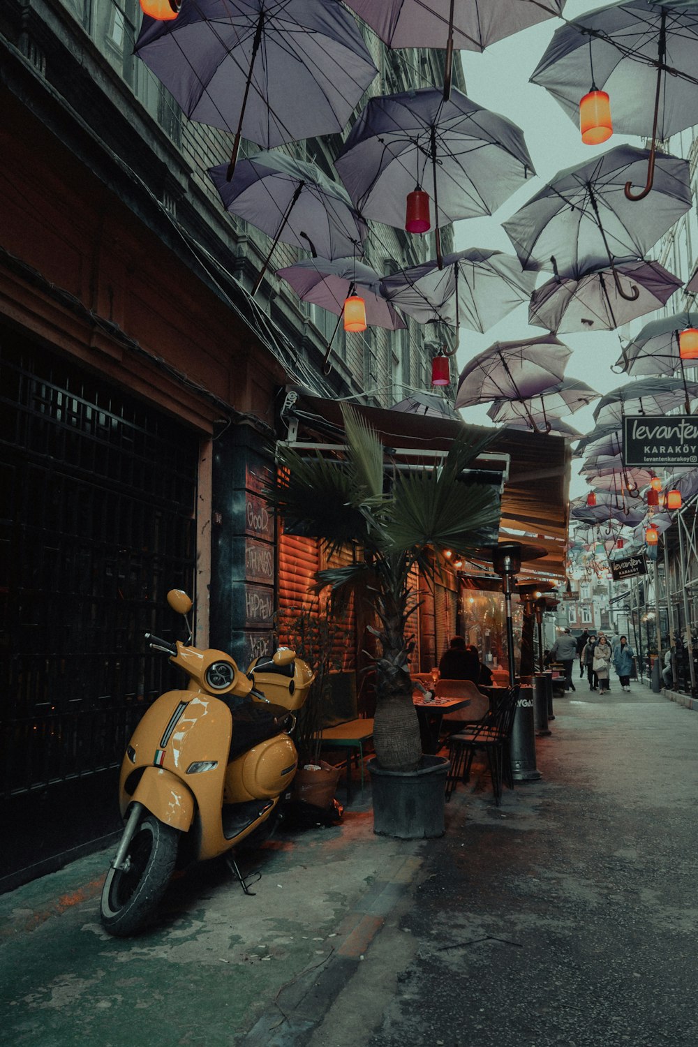 a scooter parked on the side of a street under umbrellas