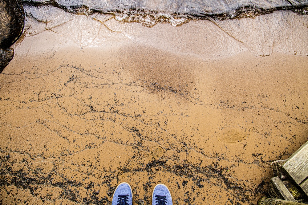 a person standing on a beach with their feet in the sand