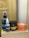 The image depicts a collection of hair care products, including a spray bottle labeled 'Lagoon Hair Tonic', a small bottle labeled 'Pre Style', and jars of 'Old School Pomade' and 'Murray's Superior Hair Dressing Pomade'. These items are arranged on a plain box with a blurred background.
