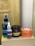 The image depicts a collection of hair care products, including a spray bottle labeled 'Lagoon Hair Tonic', a small bottle labeled 'Pre Style', and jars of 'Old School Pomade' and 'Murray's Superior Hair Dressing Pomade'. These items are arranged on a plain box with a blurred background.