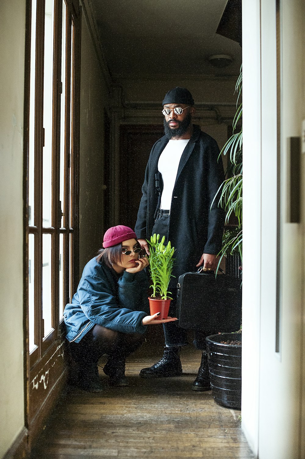 a man and a woman standing next to a potted plant