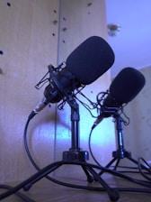 A collection of various microphone stands arranged in a well-lit studio setting.