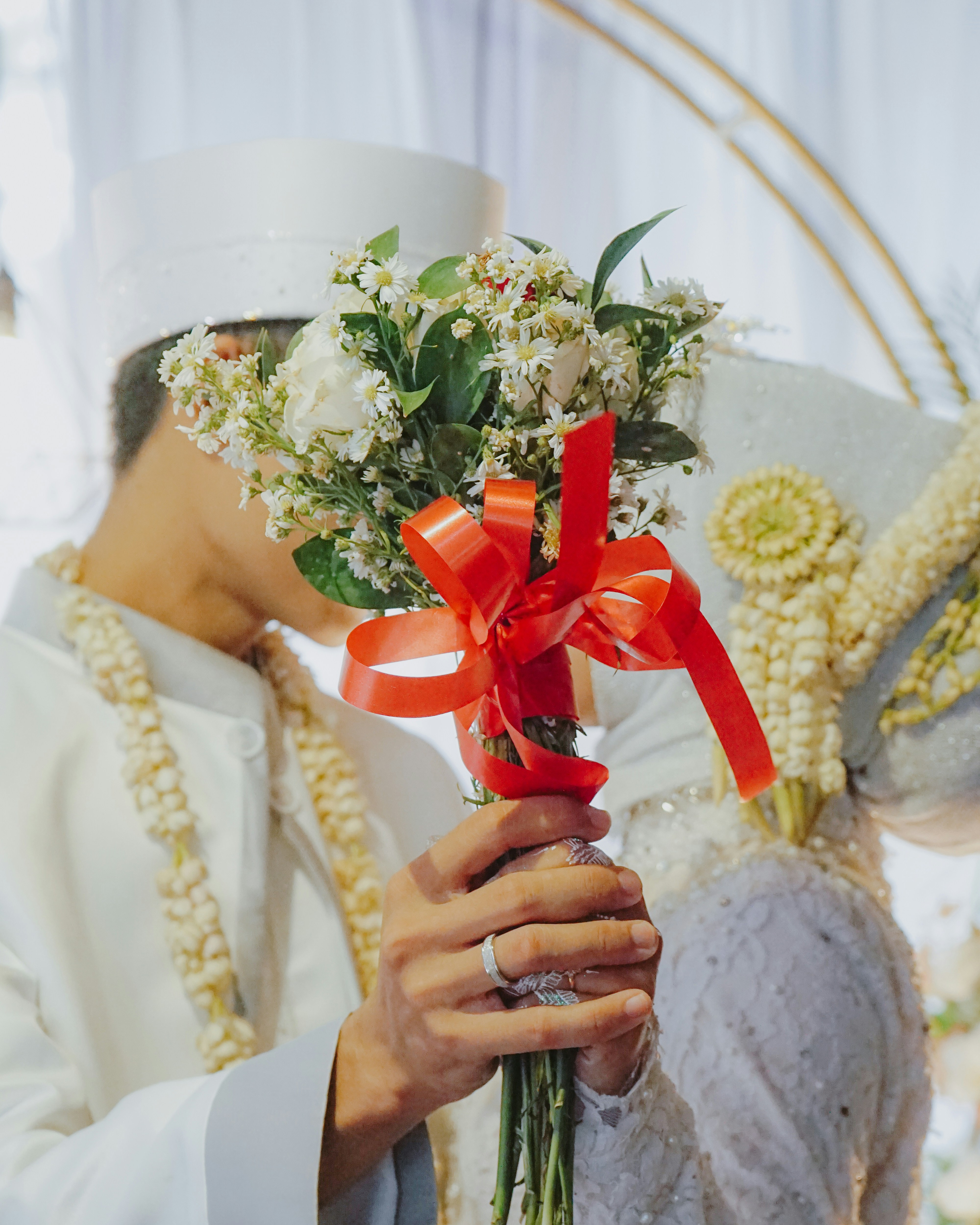 a man in a white suit holding a bouquet of flowers