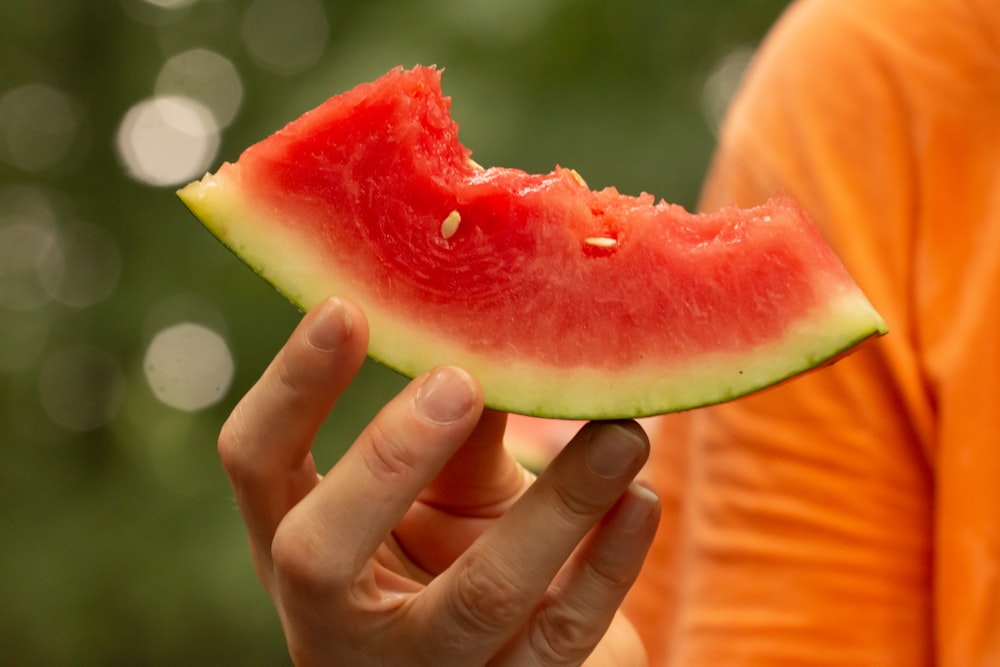 a person holding a slice of watermelon in their hand